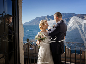alt=momenti intimi degli sposi durante il servizio fotografico professionale sul lago di garda malcesine vista lago dal castello
