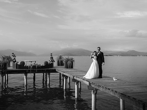alt=gli sposi sul pontile sul lago di garda per servizio fotografico