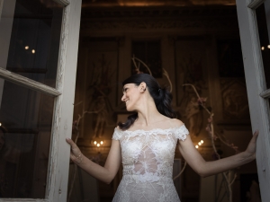 fotografo che ritrae una sposa vicino a una finesta durante i preparativi