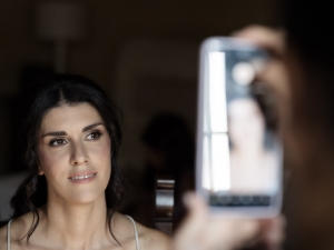 Sposa durante trucco e parrucco, immortalata nei momenti intimi dei preparativi nuziali.