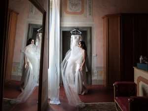 il fotografo che ritrae una sposa vicino a una finestra durante i preparativi.