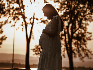 Ritratto maternità in esterni con luce morbida e paesaggio naturale