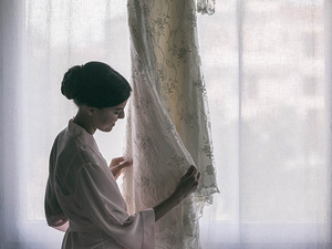alt=The bride looks at her dress before the wedding ceremony