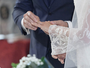 alt=The groom puts the ring on the bride