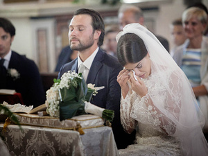 alt=The bride cries during the wedding ceremony on Lake Garda